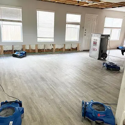 Air movers and a dehumidifier drying a Charlotte living room after the bottom of the drywall was removed