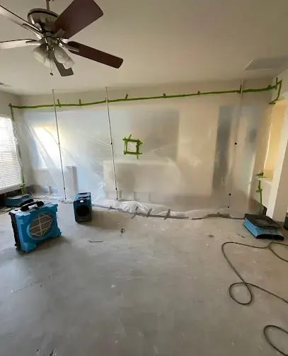 Plastic containment wall with air movers drying a room after a water leak