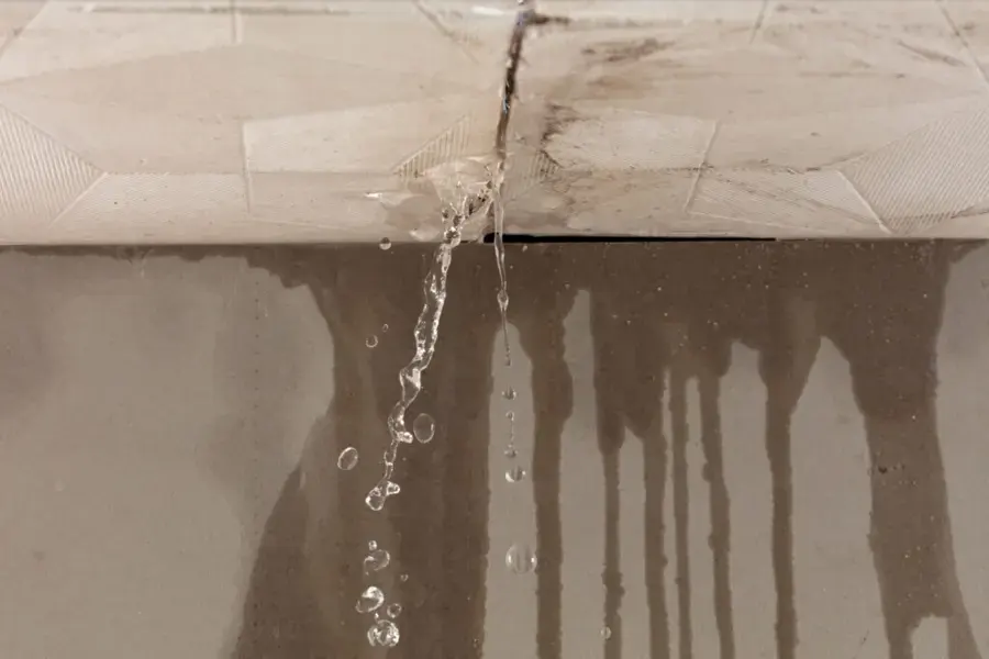 Water dripping through a ceiling seam and streaking down the wall