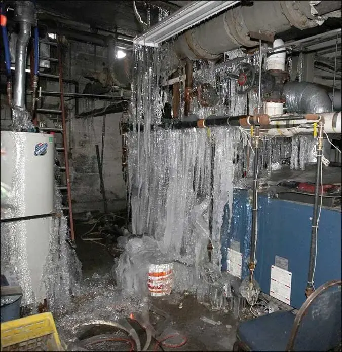 Ice built up around burst pipes in a basement mechanical room after a hard freeze